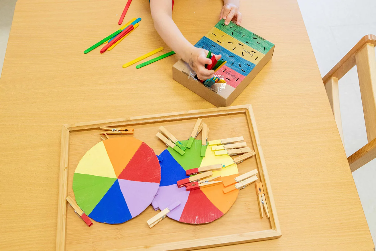 Enfant qui joue avec des jeux éducatifs en bois colorés sur une table