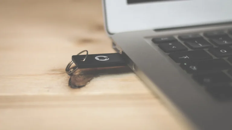 Clé de sécurité USB branchée sur le côté d'un ordinateur portable posé sur une table en bois clair