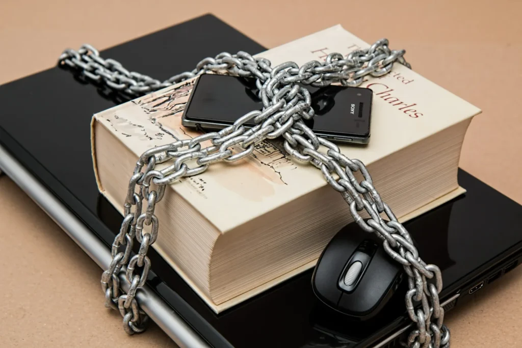 Livre et téléphone attachés par une chaîne cadenassée sur un ordinateur portable