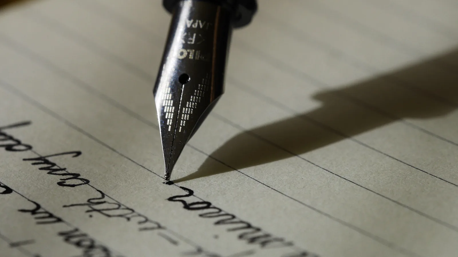 Plume d'un stylo écrivant sur une feuille de papier lignée