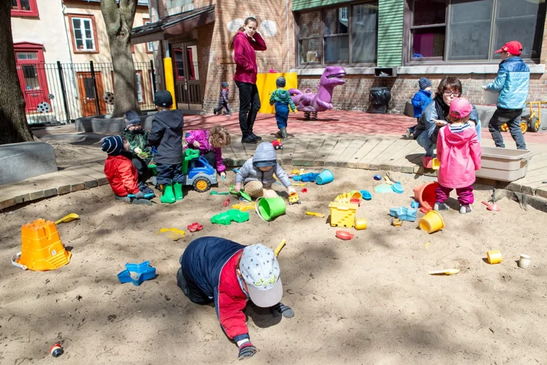 Enfants qui jouent dans un carré de sable avec leurs éducatrices