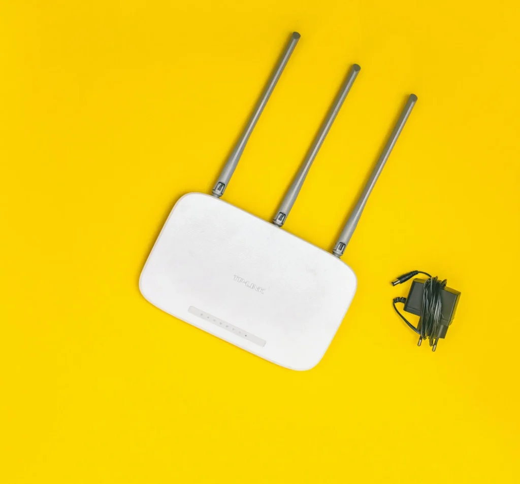 Routeur Wi-Fi blanc à trois antennes sur un fond jaune