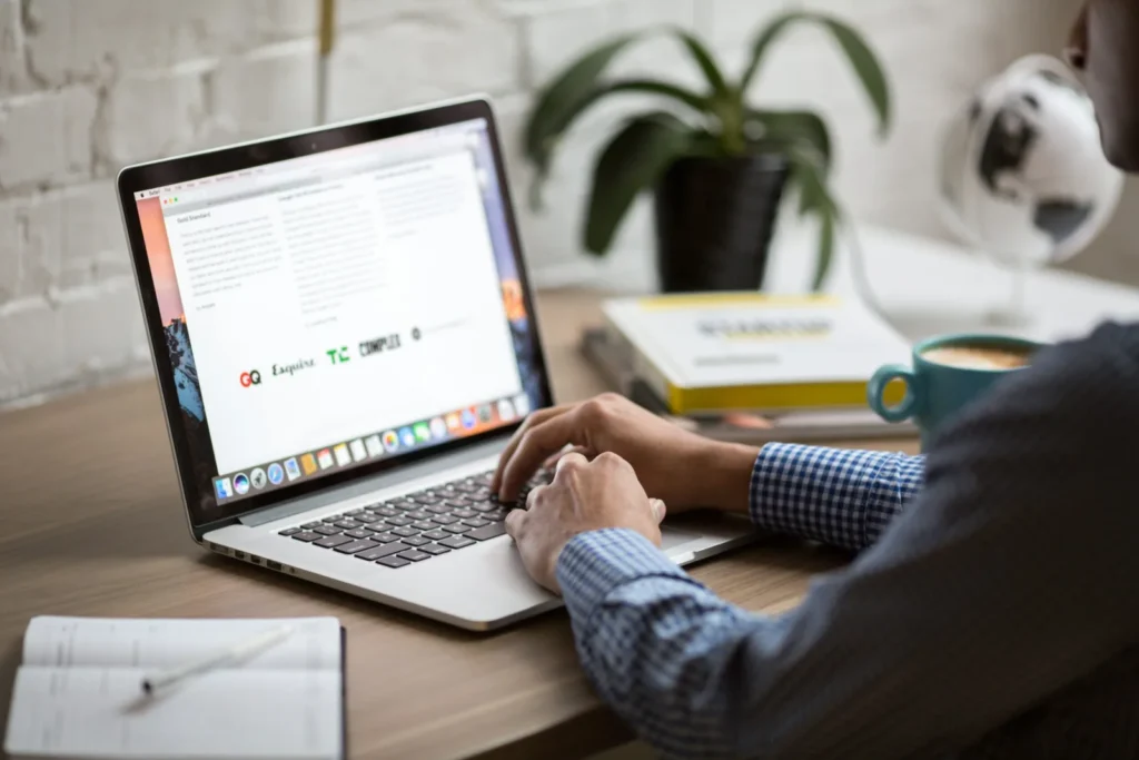 Personne qui tape sur un ordinateur portable à un bureau avec une tasse de café