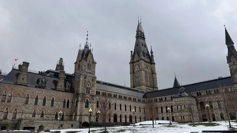 Bâtiment en pierre de la colline du Parlement à Ottawa, avec une haute tour, sous un ciel nuageux d'hiver
