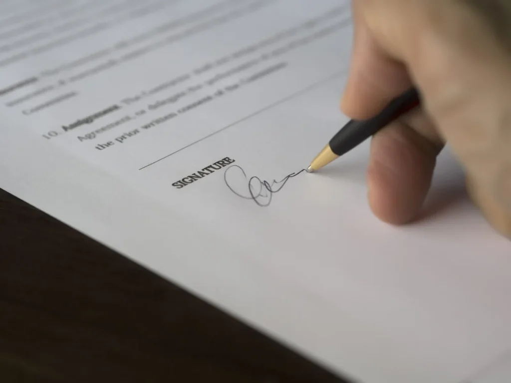 Main qui signe un contrat au crayon sur la ligne de signature