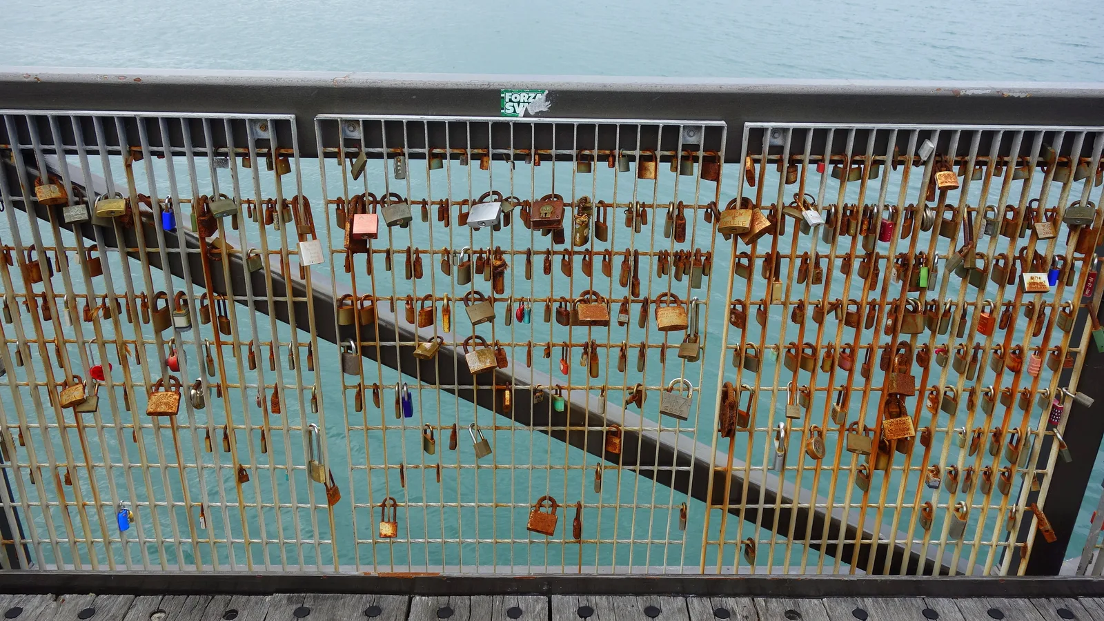 Dizaines de cadenas accrochés à une rambarde métallique devant la mer