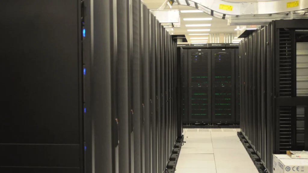 Allée sombre d'une salle de serveurs entre deux rangées de baies informatiques noires