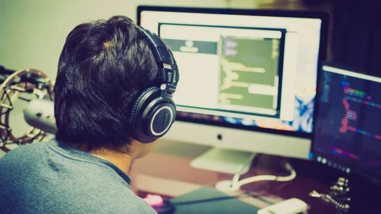 Personne avec un casque d'écoute qui travaille devant un écran d'ordinateur